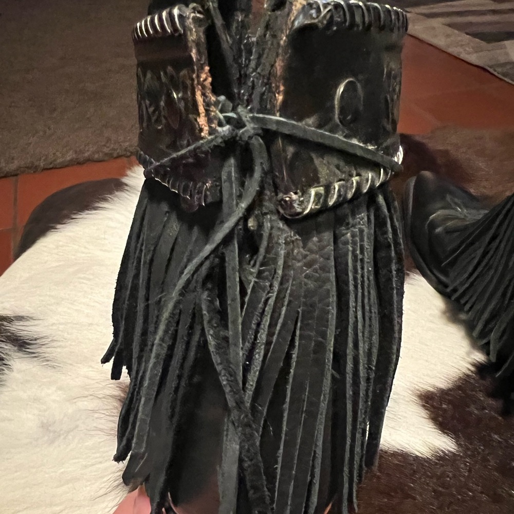 Black folded Justin boots with leather fringe and concho embellishments.